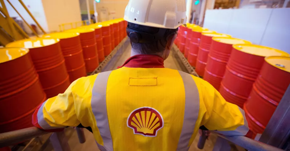 Shell Oil worker with oil barrels and Shell Logo on jacket